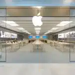 Apple Store interior with product displays and a large Apple logo.
