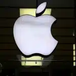 White Apple logo displayed on the front of an Apple Store at night.