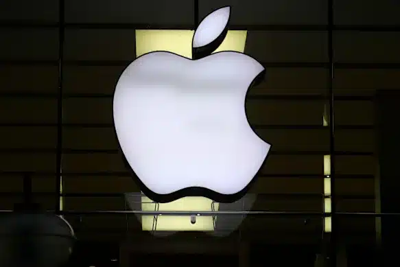 White Apple logo displayed on the front of an Apple Store at night.