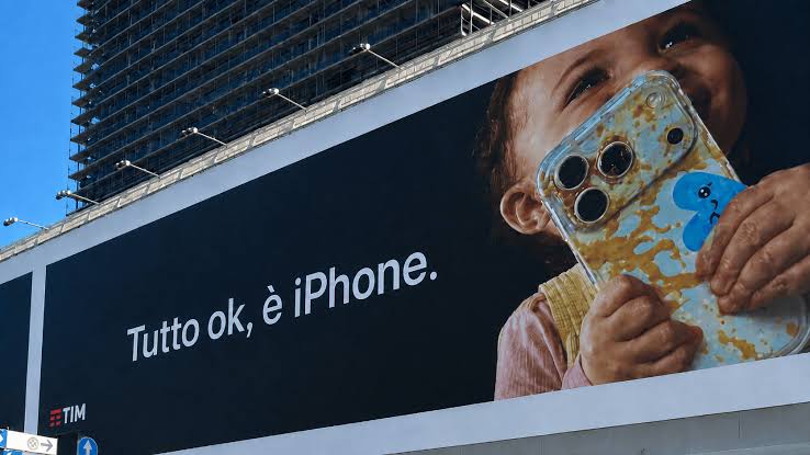 Apple billboard in Milan showing a child holding a food-covered iPhone.