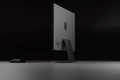 Rear view of a sleek black Apple iMac with a matching keyboard and mouse on a dark background.