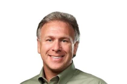 Smiling man in a green shirt against a white background.