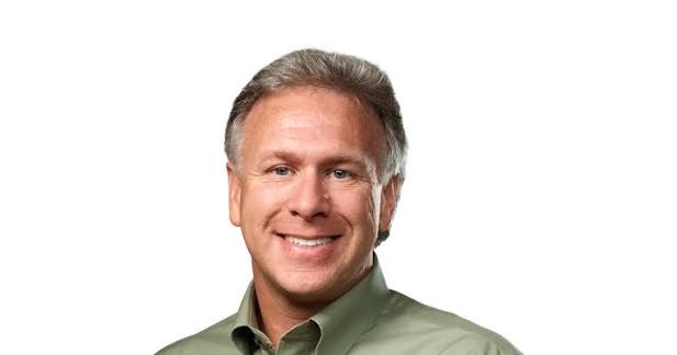 Smiling man in a green shirt against a white background.