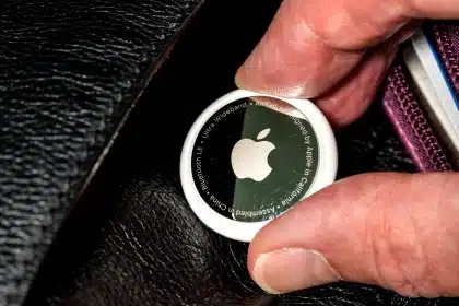 Close-up of an Apple AirTag held between two fingers.