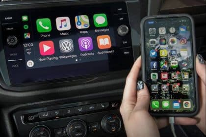 Apple CarPlay displayed on a car dashboard beside an iPhone.