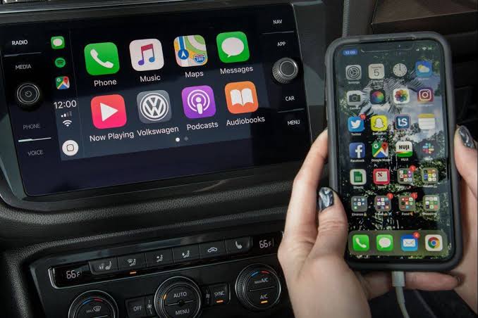 Apple CarPlay displayed on a car dashboard beside an iPhone.