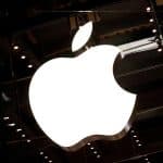 Illuminated Apple logo on a dark glass storefront.