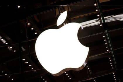 Illuminated Apple logo on a dark glass storefront.