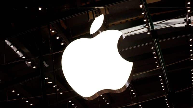 Illuminated Apple logo on a dark glass storefront.