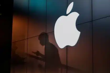 Illuminated Apple logo on a dark building wall.