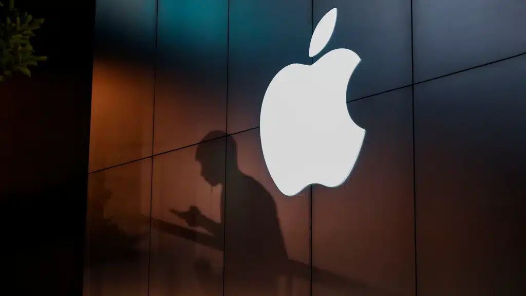 Illuminated Apple logo on a dark building wall.