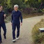 Two men walking and talking outdoors on a landscaped path.