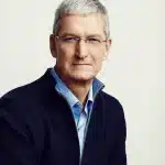 Portrait of a gray-haired man wearing glasses and a dark sweater.