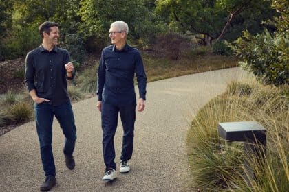 Two men walking and talking outdoors on a landscaped path.