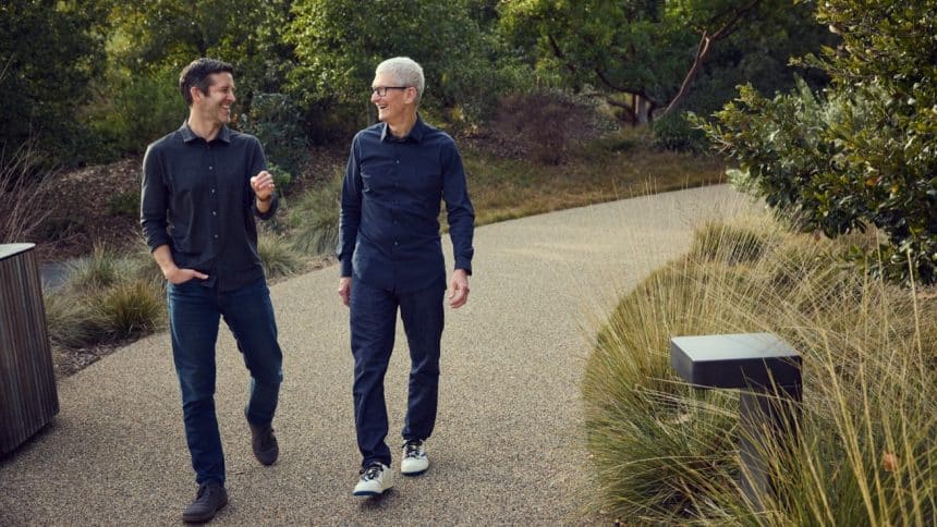 Two men walking and talking outdoors on a landscaped path.