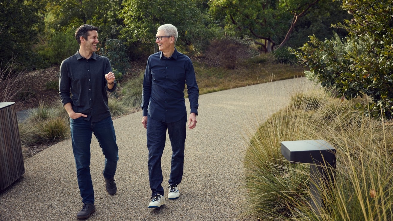 Two men walking and talking outdoors on a landscaped path.