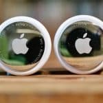 Two Apple AirTags displayed side by side on a wooden surface.