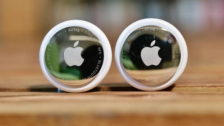 Two Apple AirTags displayed side by side on a wooden surface.