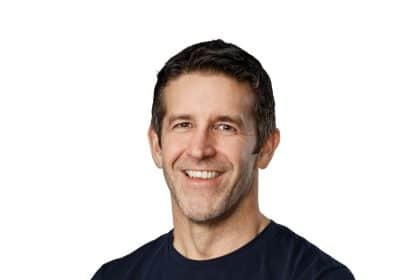 Apple CEO John Ternus smiling in a portrait against a white background.