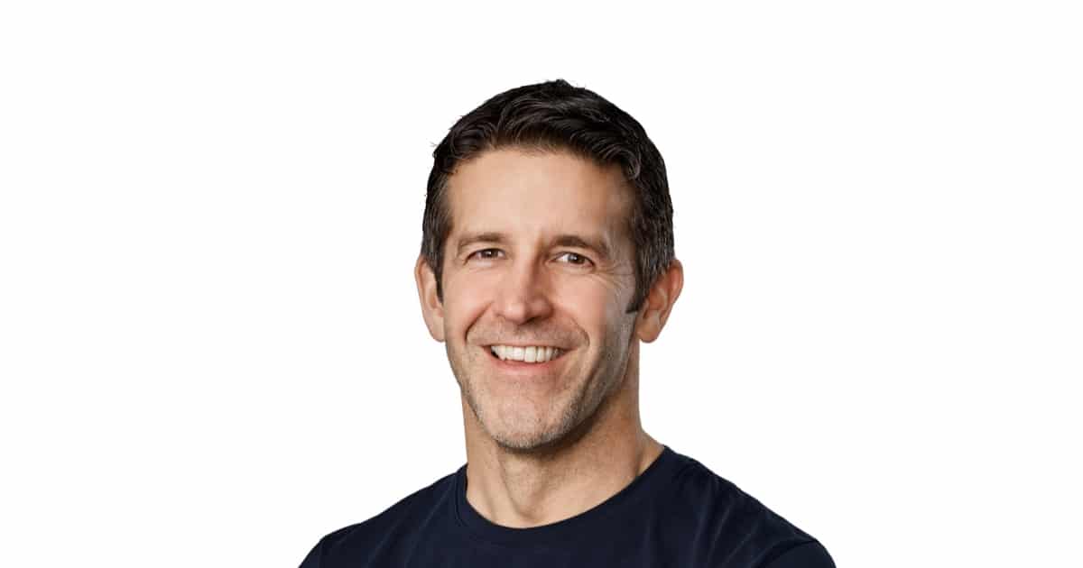Apple CEO John Ternus smiling in a portrait against a white background.