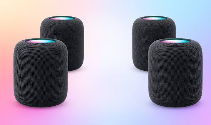 Four black HomePod speakers arranged in a surround sound setup.