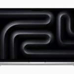 Silver MacBook Pro with a dark abstract wallpaper displayed on its screen.