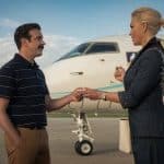 Ted Lasso and a woman exchange a handshake beside a private jet.