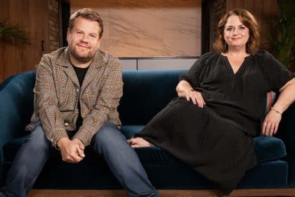 Two smiling people sitting together on a blue sofa.