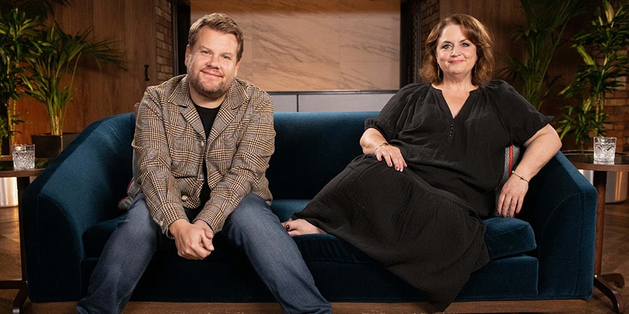 Two smiling people sitting together on a blue sofa.
