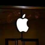 Illuminated white Apple logo on a dark storefront at night.