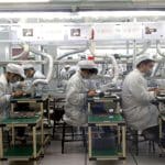 Workers assembling electronic components on a Foxconn factory production line.
