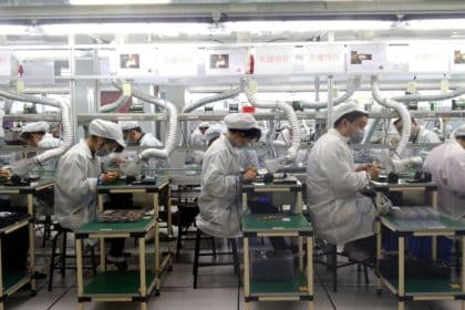 Workers assembling electronic components on a Foxconn factory production line.