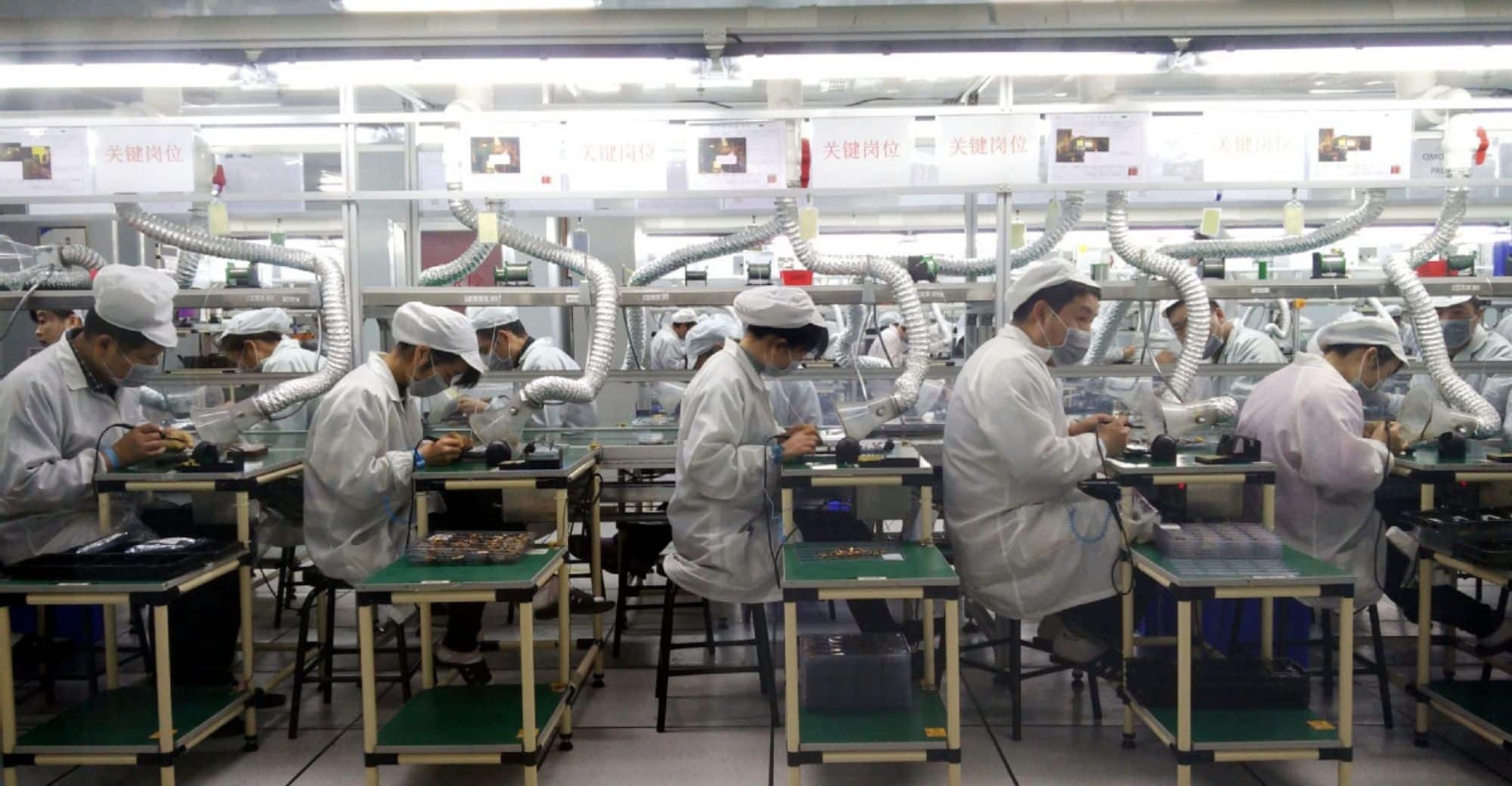 Workers assembling electronic components on a Foxconn factory production line.