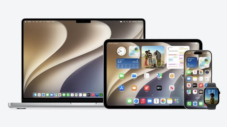 Apple MacBook, iPad, iPhone, and Apple Watch displayed together with their screens on.