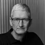Black-and-white portrait of a gray-haired man wearing glasses and a dark polo shirt.